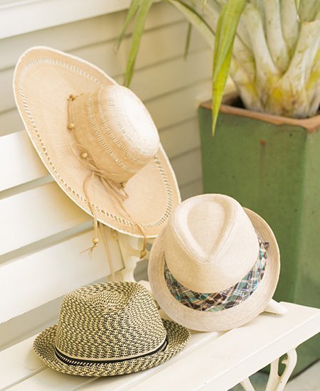 three beige weave hats from Chapel Hats Sheraton Waikiki. one broad sunbrim, and two bowler hats on a wooden bench.