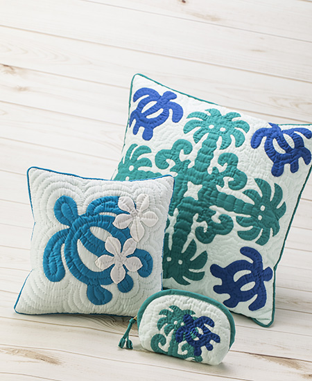 two blue, green, and white quilted Hawaiian pillows with turtle motifs by Moana Quilts