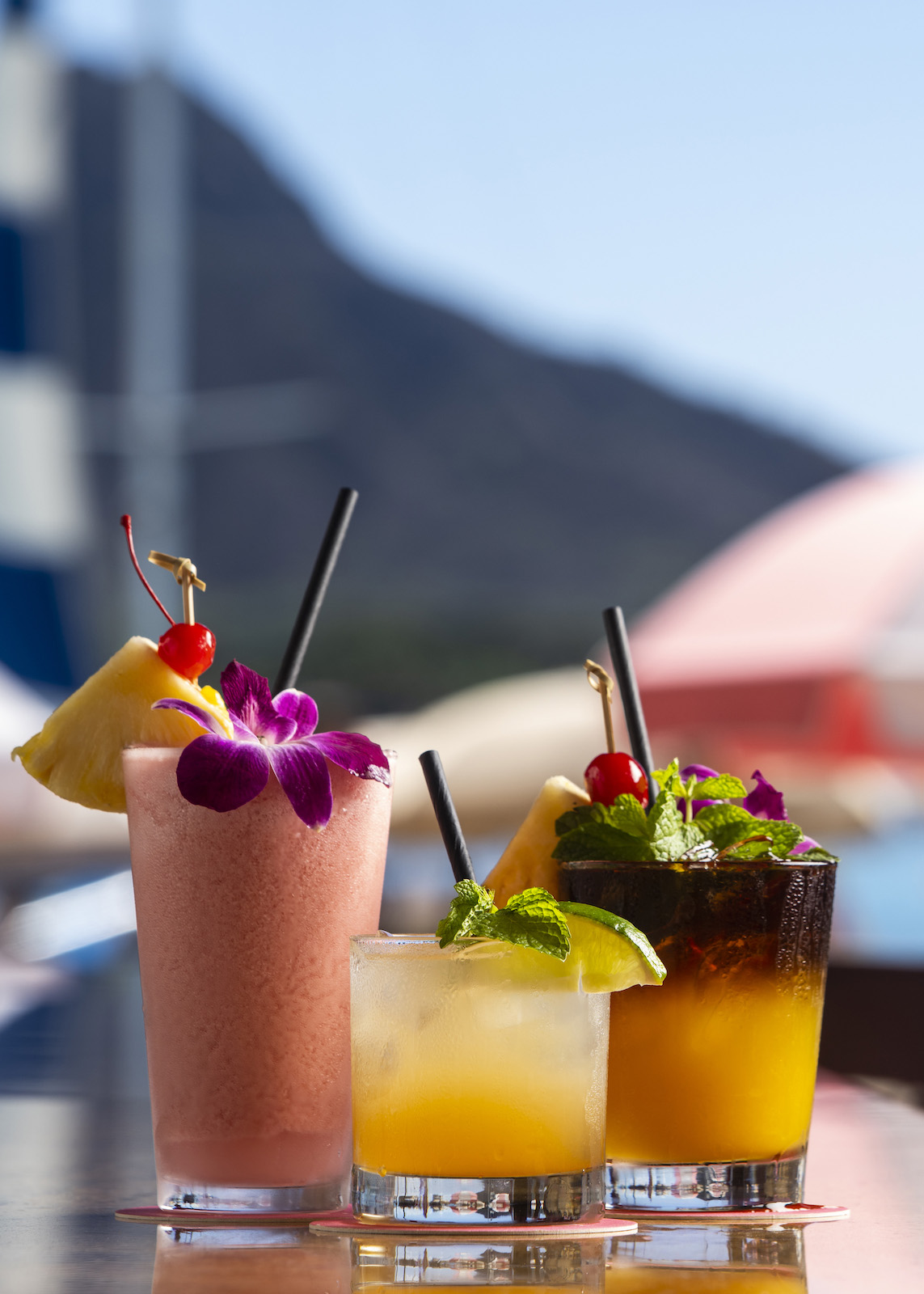 The world-famous mai tai cocktail at The Royal Hawaiian with Diamond Head in the background