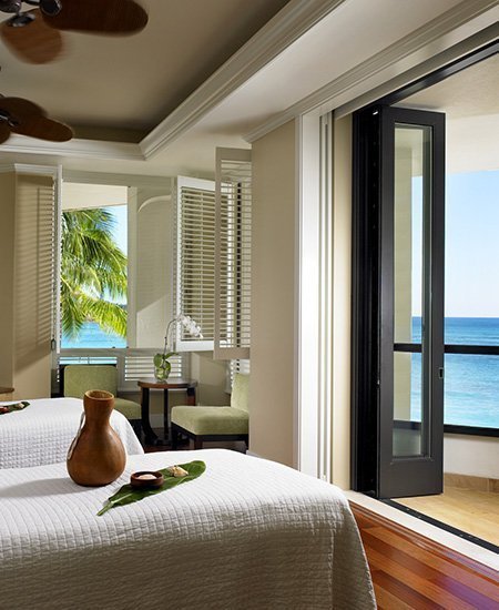 interior photo of the couples massage room at Moana Lani Spa, showing two comfortable-looking massage beds, and an open window overlooking Waikiki beach