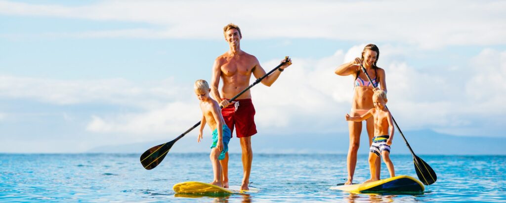 family enjoying a stand up paddling session in the ocean