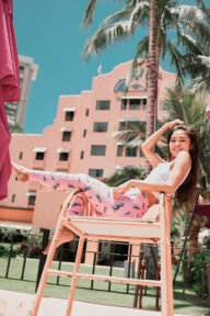 Female lounging in a chair wearing pink yoga leggings and a white spaghetti strap top