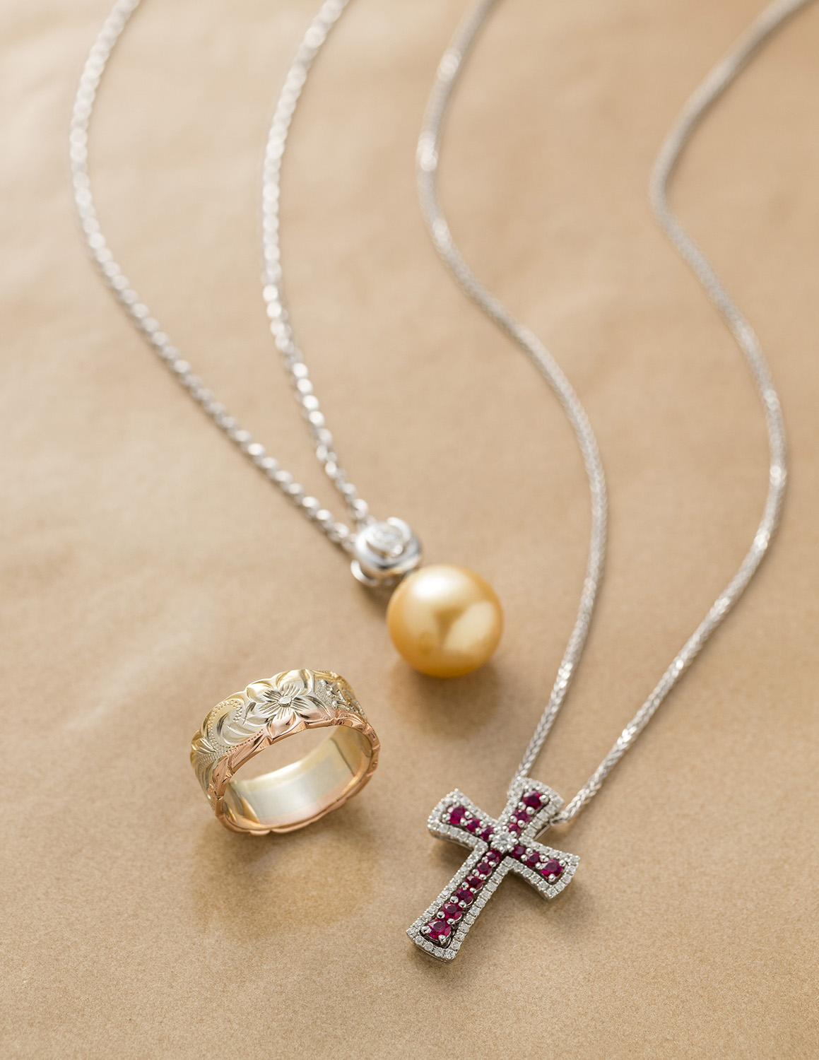 Tri-color Hawaiian ring, white pearl necklace, and jeweled cross necklace