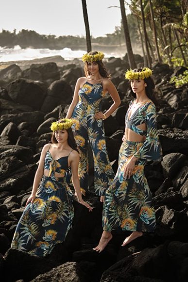 Kahulale’a, three women standing on a rocky ocean coastline wearing flower haku lei and green hawaiian print aloha wear